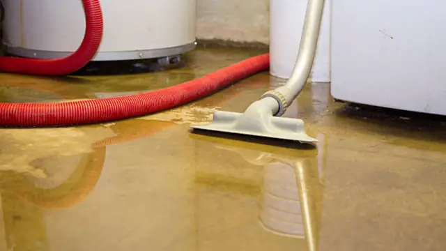 Wet vacuum pulling water off the floor beside a water heater